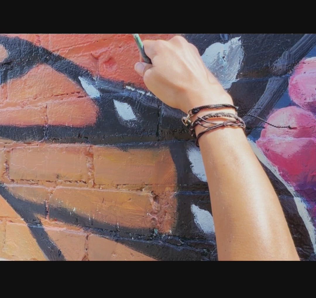 Load video: Video shows murals completed by krystal michelle mural studio. It pictures a few still images of her painting and her on a lift. The first portion pictures her painting a portion of a large monarch butterfly, followed by a large monochromatic landscape mural with trees and landmarks specific to Peachtree city such as the peachtree city bridge and gold cart trials, the video finishes with a walk through an immersive tunnel mural that was painted to look like a larger than life paradise scene.